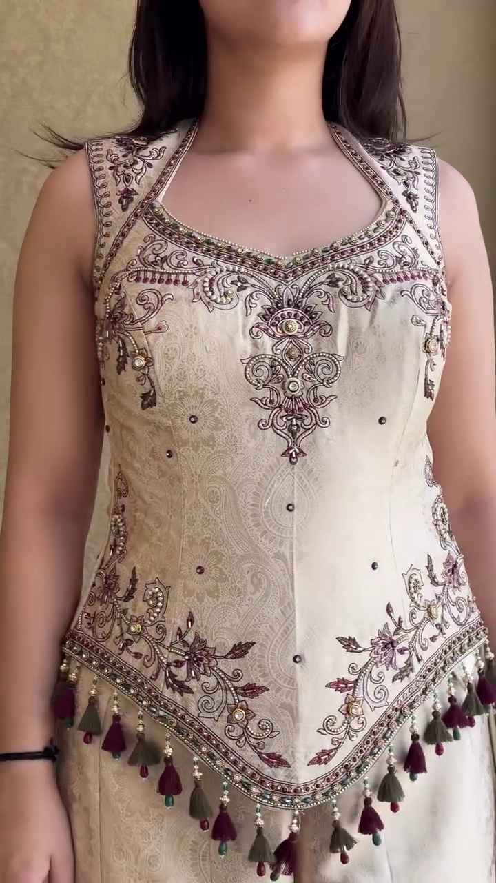 Elegant Ivory Cream Embroidered Sharara Style Palazzo Suit with Designer Sleeveless Peplum Top, Traditional Tassel Detailing, and Matching Dupatta for Weddings, Festivals, and Special Occasions